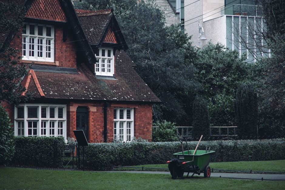 A person wearing a white glove and a wristwatch is holding a large white bag filled with garden waste, including small branches, green foliage, and shredded plant material. A rusty garden spade with a